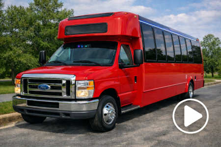 Red Ford shuttle bus with tinted windows and chrome grille parked on a paved road.